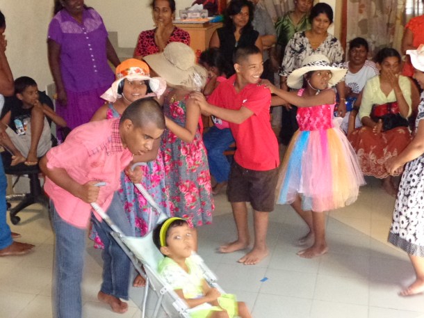 The children performing at a party at E.A.S.E. They are enacting a children's song about a doll. Little Dulhara who has severe Cereral Palsy and is unable to walk though she can talk is playing t